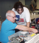 Instructor working with a student taking a computer apart